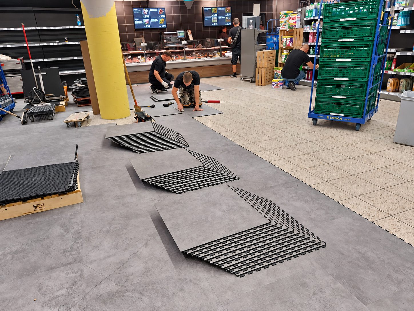 Verlegung im Supermarkt während des Betriebs, vorn die Platten in Betonoptik, hinten die Regale