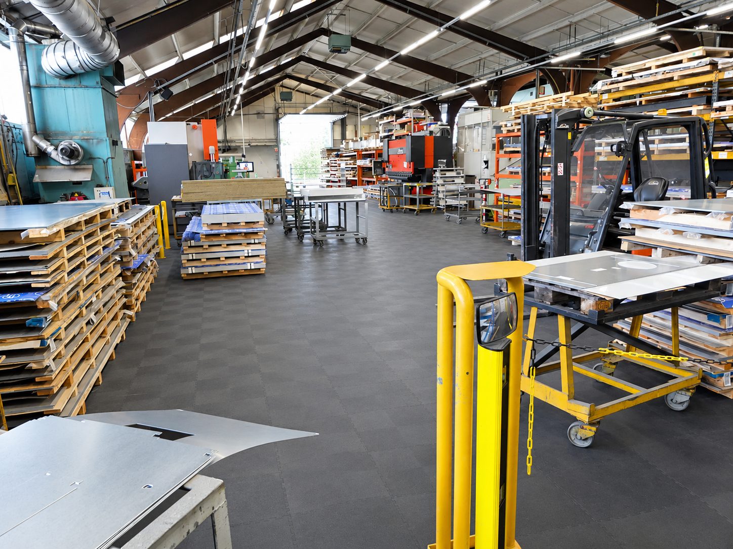 Produktionshalle mit Materialwagen und Blechtafeln auf dunkelgrauem Bodensystem