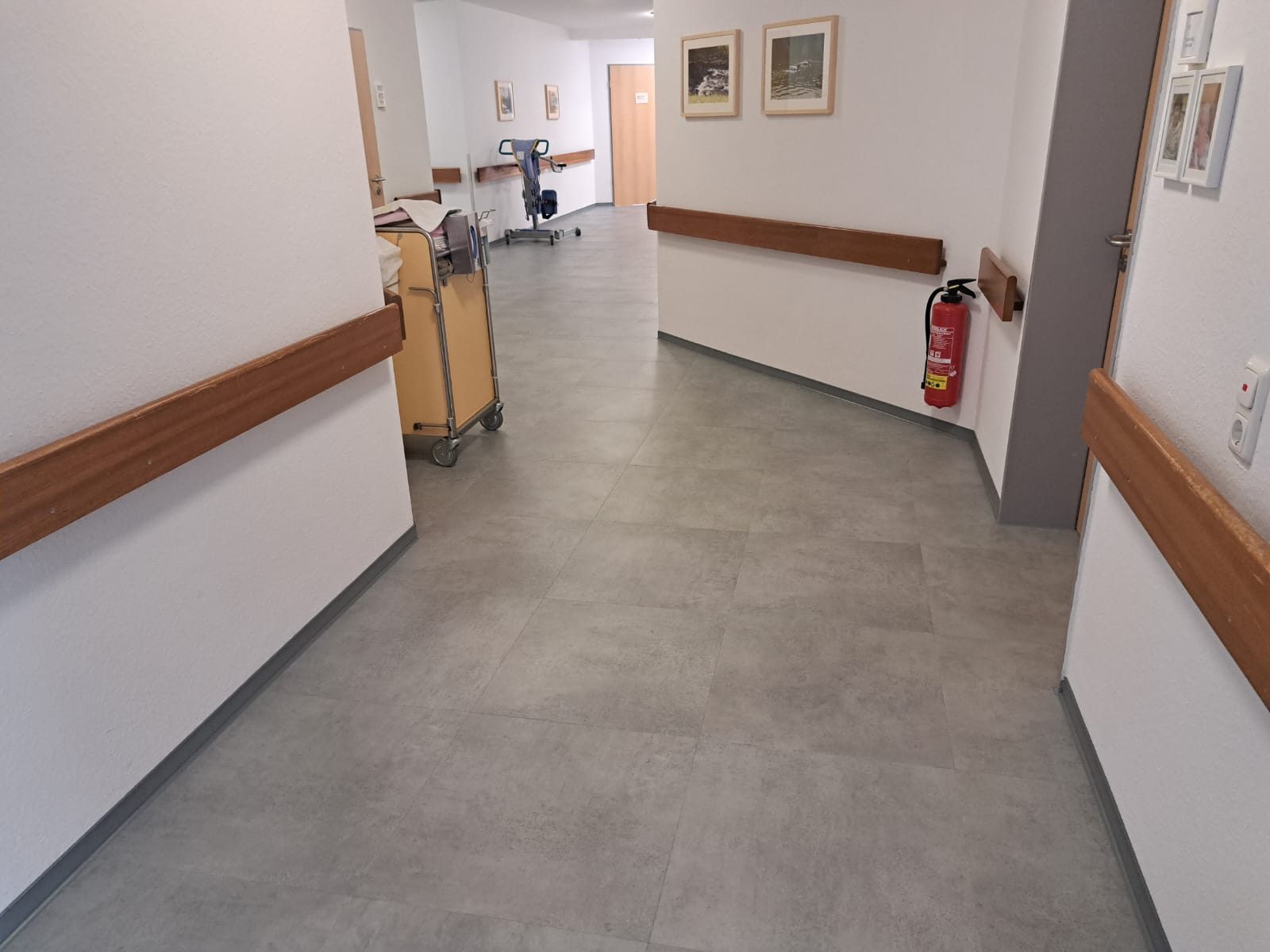 Flur einer Pflegeeinrichtung mit Handläufen auf Boden in Betonoptik