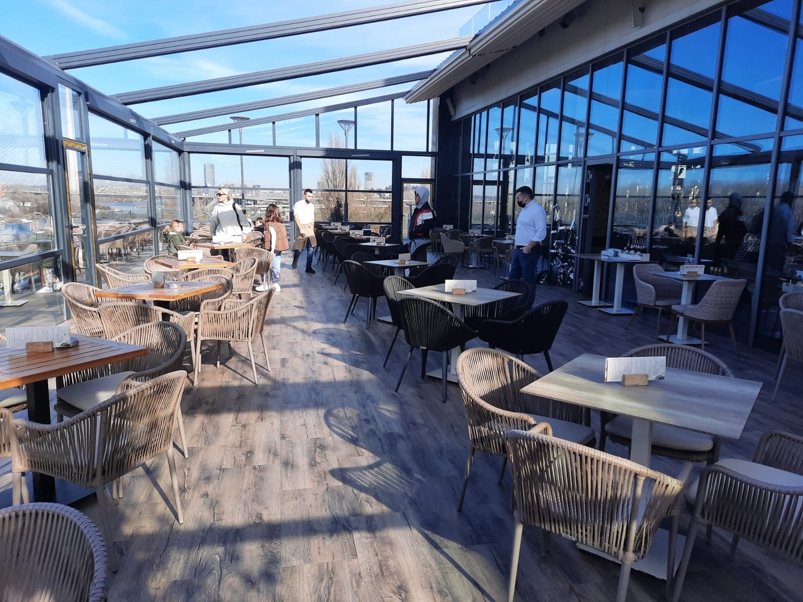 Wintergarten eines Restaurants mit Tischen und Stühlen auf Boden in Holzoptik