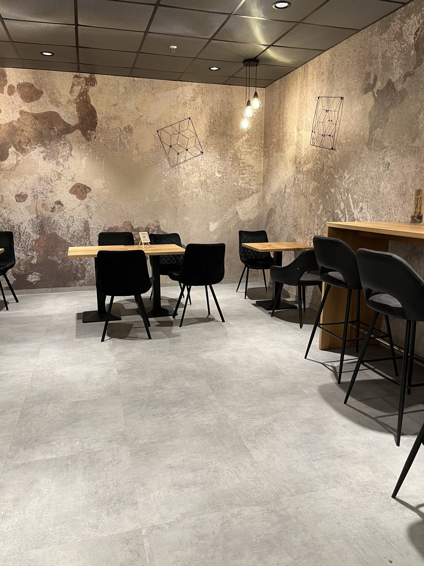 Café mit Tischen und Barhockern auf Boden in Betonoptik