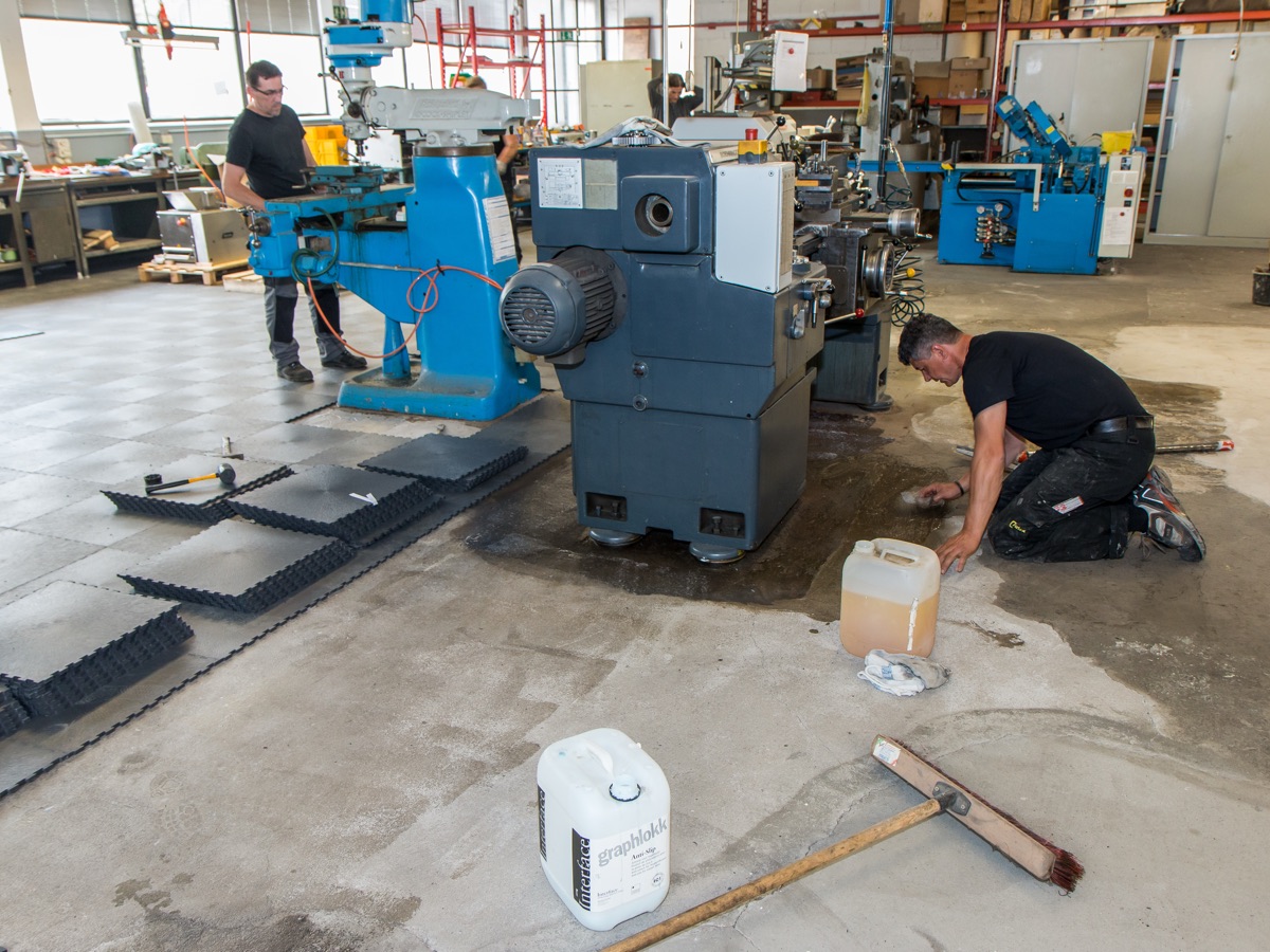 Verlegung von Bodenplatten neben einer laufenden Fräsmaschine