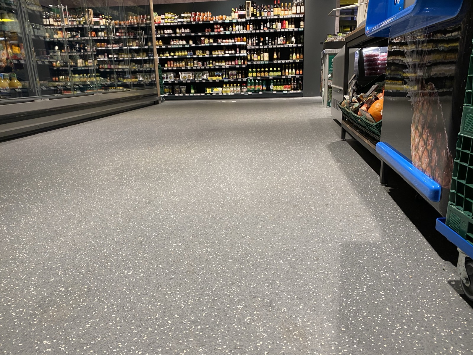 Verkaufsgang eines Lebensmittelmarkts mit gesprenkeltem Boden aus Design-Puzzle-Platten